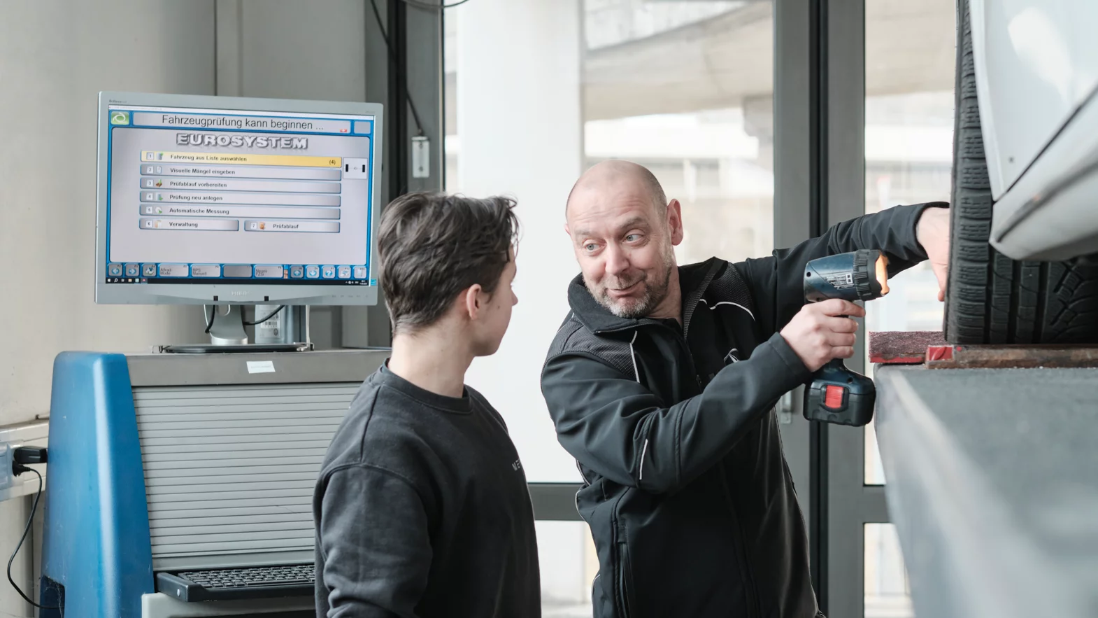 Automobil-Mechatroniker:in EFZ Fachrichtung Nutzfahrzeuge mit dem Berufsbildenden während der Arbeit.